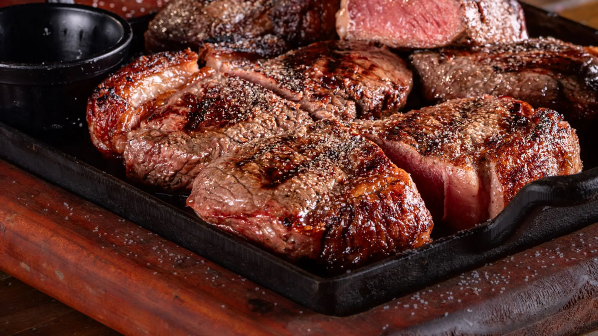 Tábua de cortes Angus na chapa de ferro, com molhos Dona Nice ao fundo